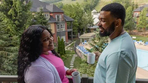 a man and woman holding coffee cups on a balcony at Blue Mountain Resort