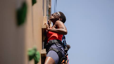 A woman climbing the Lumber Lanes Climbing Wall at Blue Mountain Resort