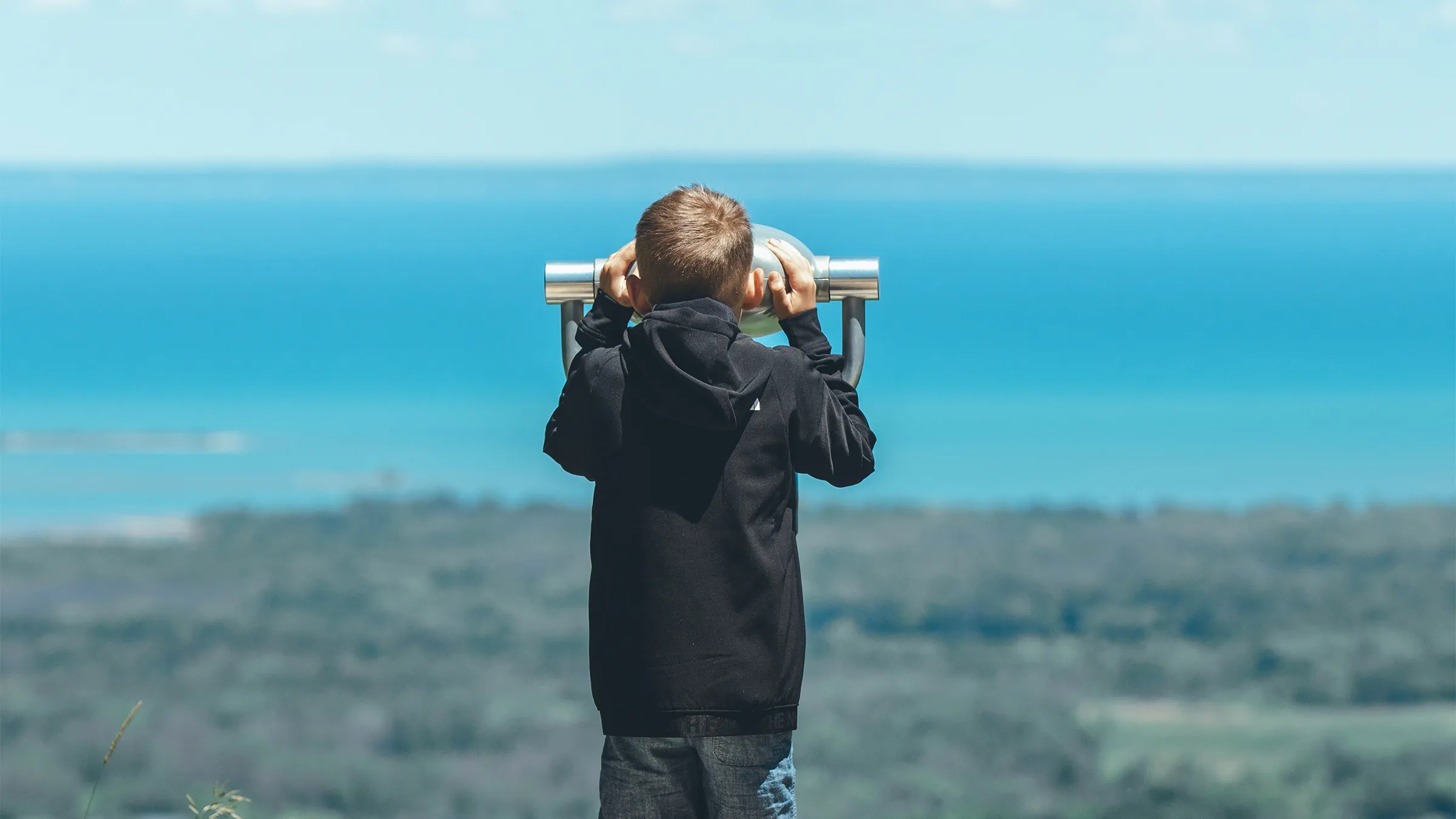 A kid looking at the view with a binoculars at Blue Mountain