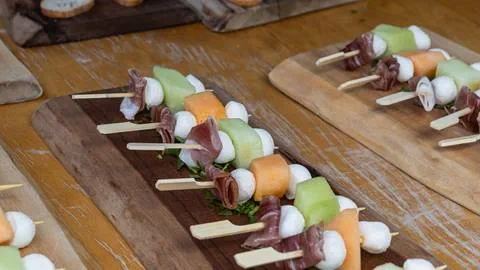 skewers with meat and fruit on a wooden board