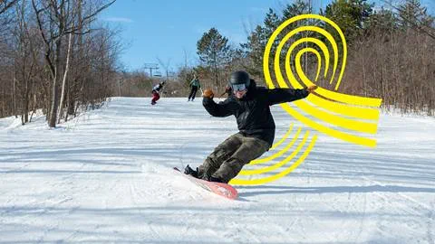 Snowboarder performing a carve on a slope with stylized yellow graphics in the background.
