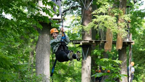 Woman ziplining through the Timber Challenge High Ropes Course at Blue Mountain
