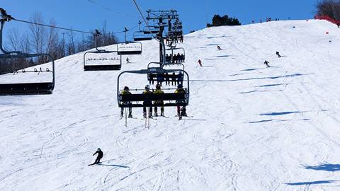 People on South lift with skiers riding down Blue Mountain hill