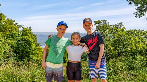 Three young people posing for a picture on a hill.