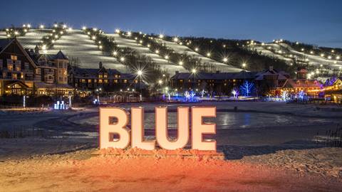 A blue sign is lit up in front of a ski resort.