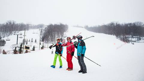 Three skiers posing for a picture on a snowy slope.