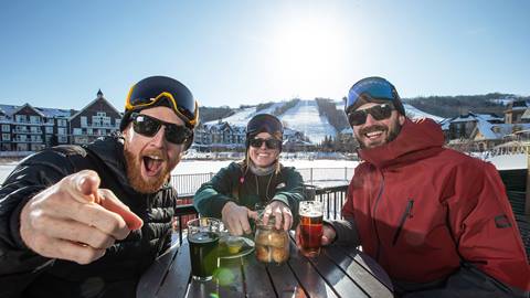 Three skiers sitting at a table with drinks.