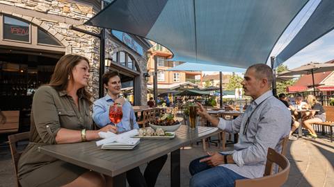 Three people enjoying drinks and food at Blue Mountain Resort