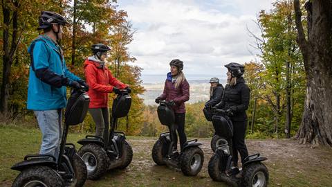 A group of people on segways in the woods.