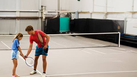 a person holding a racket on a court