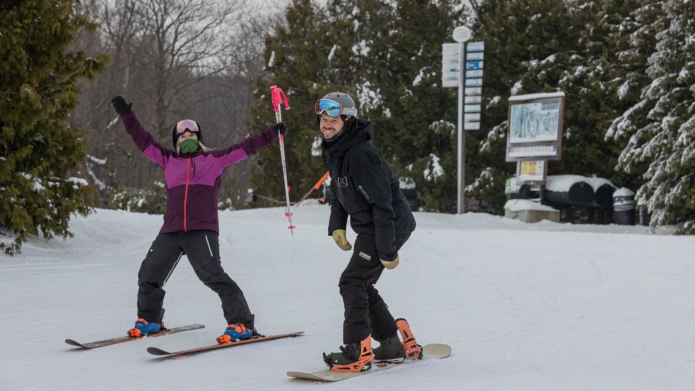 Friends smiling on skis and snowboard at top of Blue Mountain hill