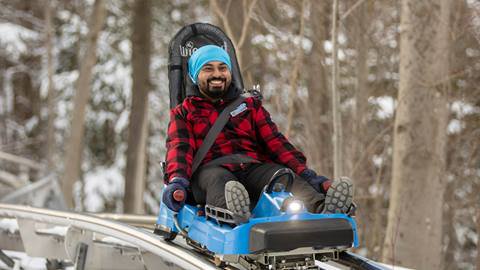 A man riding a blue roller coaster in the snow.