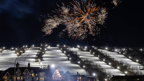 A ski slope is lit up with fireworks. 	