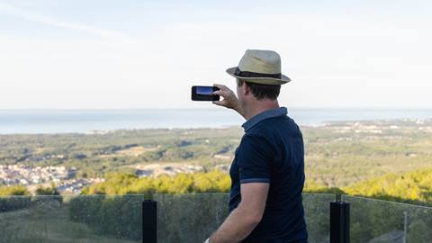 A man taking a photo with his phone of the beautiful view at Blue Mountain Resort