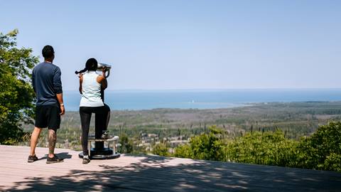 a man and woman looking through the binoculars in the Explore Park at Blue Mountain Resort