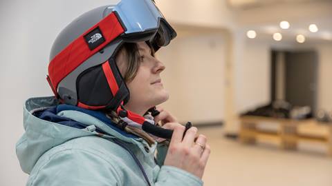A woman wearing a ski helmet in a room.