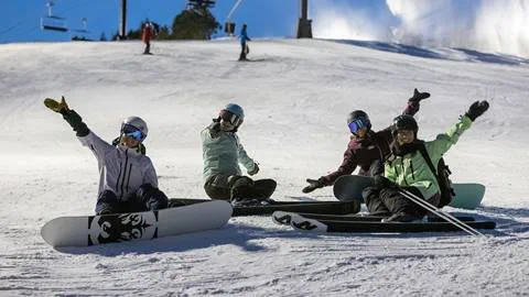 A group of people sitting on snowboards on a snowy slope.
