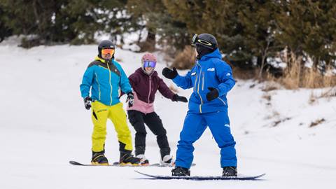 Three people are snowboarding on a snowy slope
