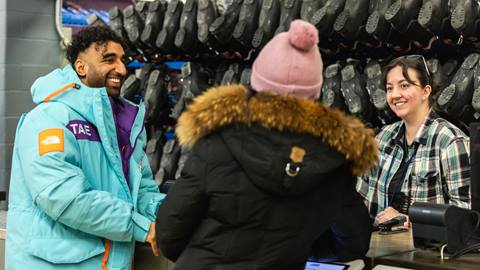 Two people standing in front of a shoe store.