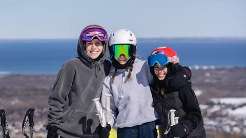 Three children posing for a photo on a ski slope.
