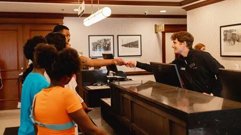 Front Desk agent shakes hands with a group of people at a hotel.