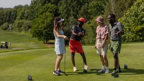 A group of people playing golf on a green field.