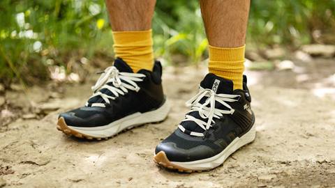 A man wearing a pair of black hiking shoes and yellow socks.