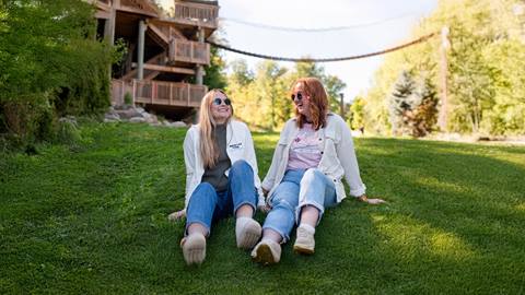 two people sitting on the grass in the Adventure Park at Blue Mountain Resort