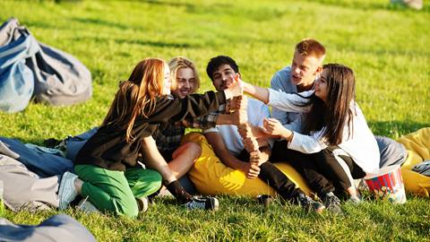 A group of young people sitting on a grassy field.