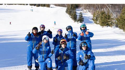 A group of people in blue ski suits posing for a picture.