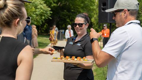 A Blue Mountain employee holding a tray of food offering to guests
