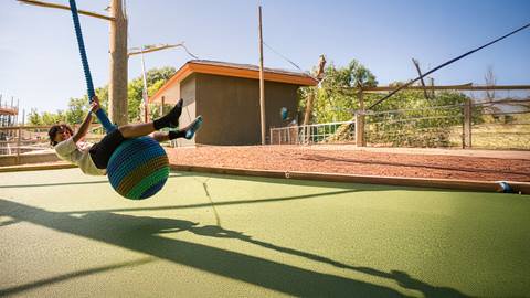 a boy swinging on the Cocoon Crawl Playscape