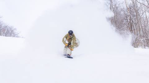a snowboarder riding through some pow