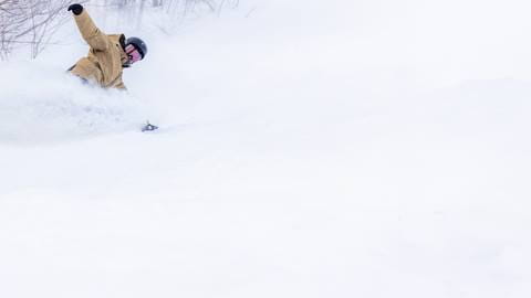 a snowboarder riding through powder