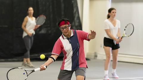 A man is hitting a tennis ball with a racket.