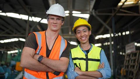 Two construction workers posing for a photo in a factory.