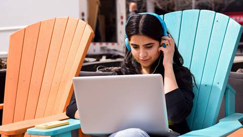 A girl using a laptop and with headphones on 