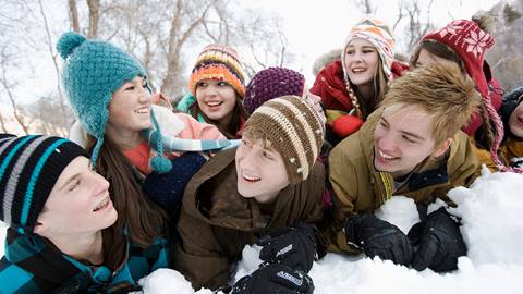 A group of young people laying in the snow.