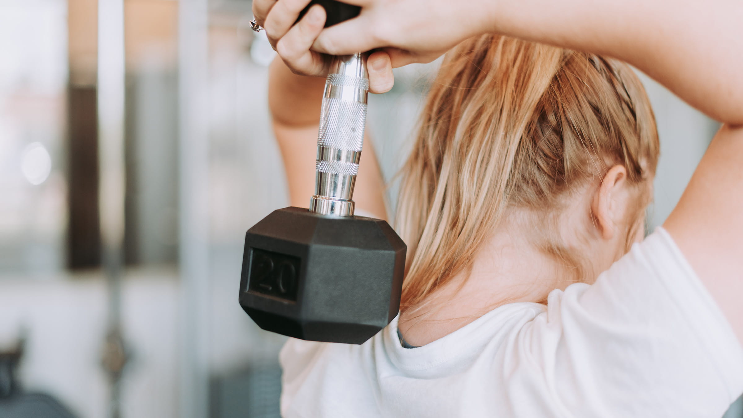 A woman lifting a dumbbell in a gym.