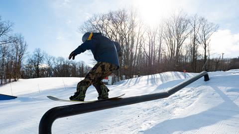 A person riding a snowboard on a rail.