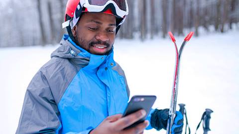 A man holding skis and a cell phone.