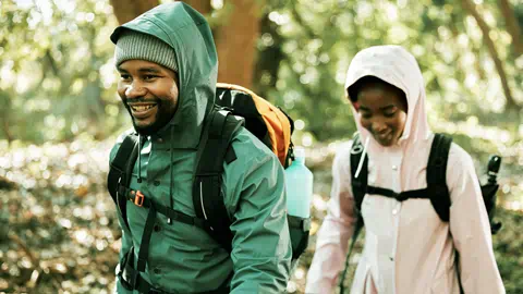 Two hikers walking through a forest with backpacks.