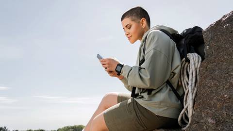 A woman sitting on a rock looking at her phone.