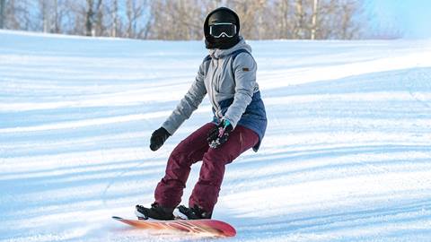 A person riding a snowboard down a snowy slope.