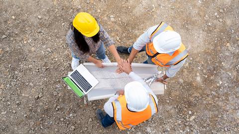 A group of construction workers shake hands with a laptop.