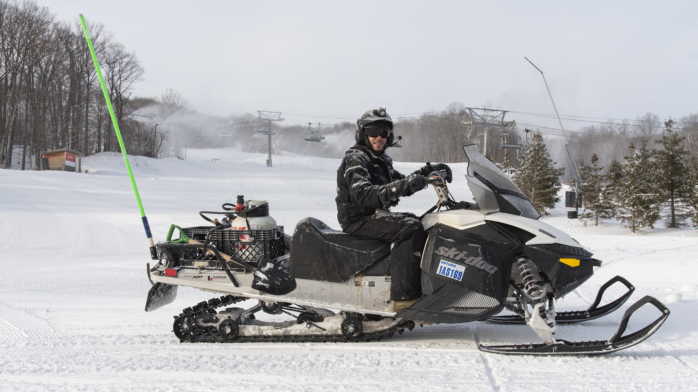 Snowmaker sitting on a snowmobile smiling on the run at Blue Mountain Resort