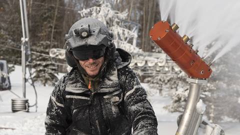 Snowmaker smiling in front of a snow gun at Blue Mountain Resort