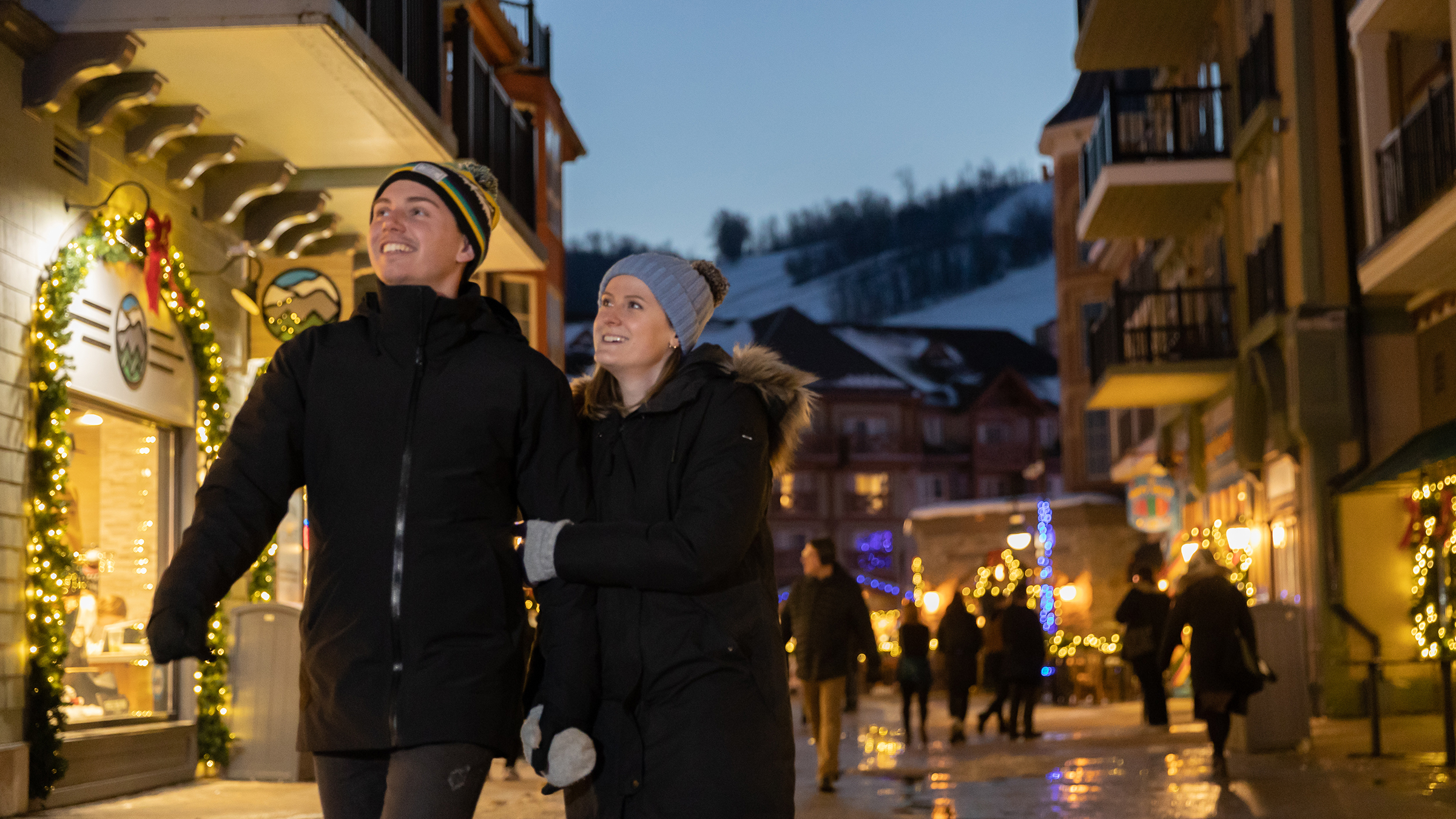 Pair of people walking through the Blue Mountain Village in the evening in Winter
