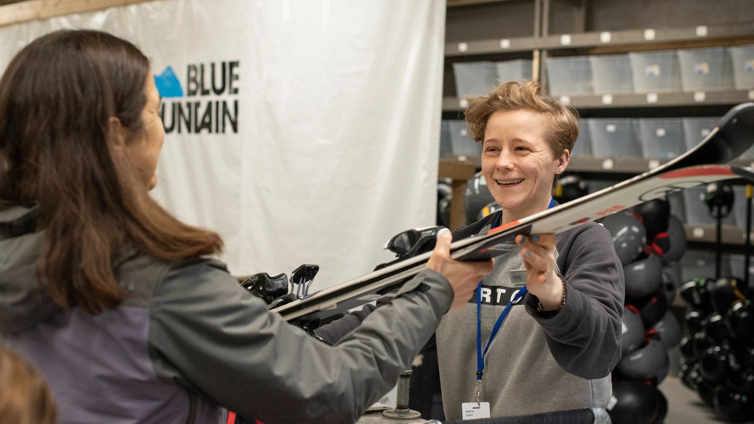 Staff in rentals handing over pair of skis to customer