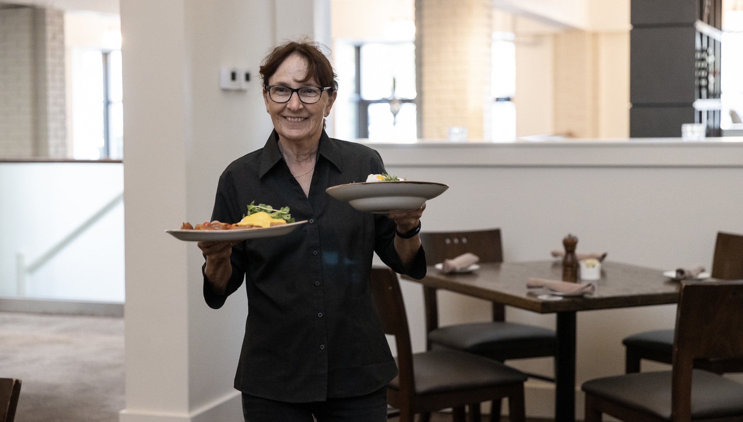 Server at Blue Mountain Pottery Restaurant serving plates of breakfast